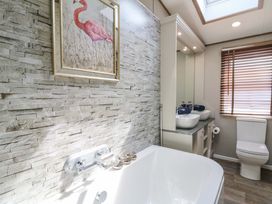 A bathroom with a bathtub, toilet, and sinks at The Beaumont No 34 in New Quay