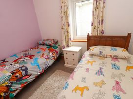 A bedroom with two beds and a bedside table at 2 Llainwen in Ty Croes