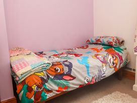 A bed with a character-themed bed sheet and pillows at 2 Llainwen Ty Croes