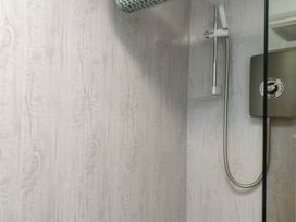 A shower with a glass panel and wall at 2 Llainwen Ty Croes