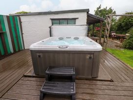 A hot tub with steps on a wooden deck in an outdoor area at 2 Llainwen in Ty Croes