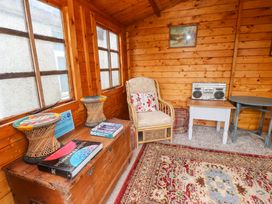 A snug with a chair, table, chest, and boombox at 2 Llainwen Ty Croes