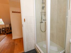 A bathroom with a shower and a chair at Fairways House in Weymouth