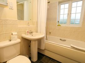 A bathroom with a toilet, sink, bath and window at Fairways House in Weymouth