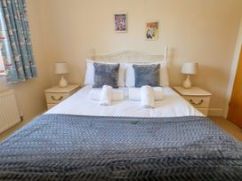 A bedroom with a bed, bedside tables, and decorative curtains at Fairways House in Weymouth