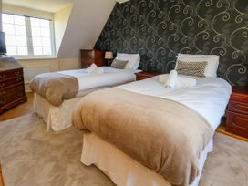 A bedroom with twin beds and a dresser at Fairways House in Weymouth