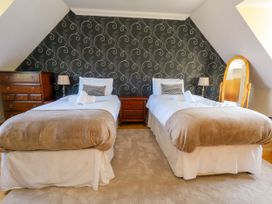 A bedroom with two beds and wooden furniture at Fairways House in Weymouth