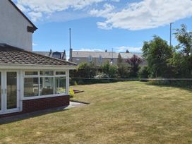 A garden with a conservatory and houses in the background at 13 Seafield Road