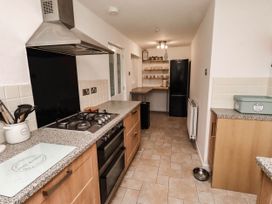 A kitchen with stove, refrigerator and shelves at Bari House in Seahouses