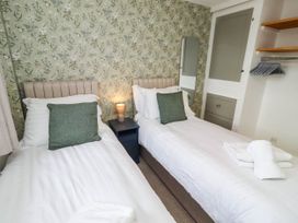 A bedroom with two single beds and a bedside table at Bari House in Seahouses