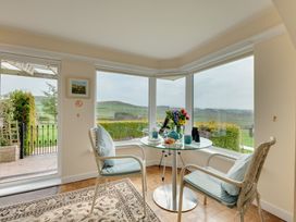 A conservatory with a table and chairs overlooking the garden at The Granary in Alnwick