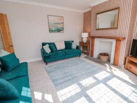 A living room with teal sofas and a rug at 60 Muston Road in Filey