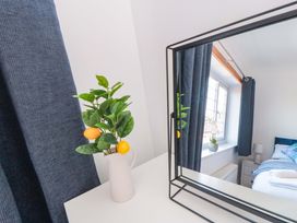 A bedroom with a mirror and a vase of flowers at 60 Muston Road in Filey