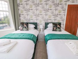 A bedroom with twin beds and a palm tree wallpaper at 60 Muston Road in Filey