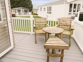 A deck with wooden chairs and a table at Kelly's Retreat in Scarborough
