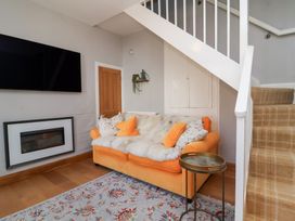 A living room with an orange sofa and television at Seacroft Cottage in Combe Martin