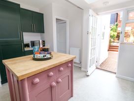 A kitchen with a pink island and dark green cabinets at Otter Cottage in Weymouth