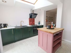 A kitchen with a pink island and green cabinets at Otter Cottage in Weymouth