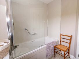 A bathroom with a bathtub shower installation and a wooden chair at 31 Bull Lane Dorchester