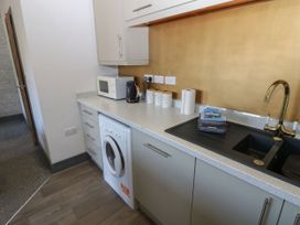 A kitchen with a washer, microwave, kettle, and sink at Quayside Apartments in Whitehaven