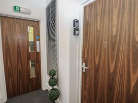A hallway with doors and a floor plant at Quayside Apartments in Whitehaven