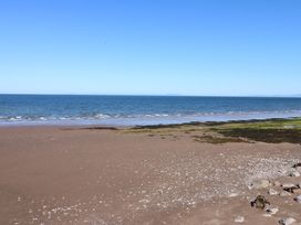 A beach scene with sand, rocks, and water at Quayside Apartments in Whitehaven