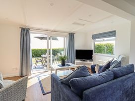 A living room with a television and a sliding door to the patio at Stella Maris in Torpoint