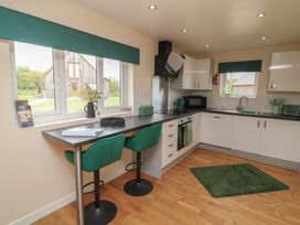 A kitchen with a countertop, stools, and appliances at James Ville Marina Lodge 22 in Brigg