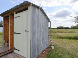 A shed with a wooden door in a grassy area at Robin in Monewden near Otley, Suffolk