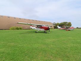 Two airplanes parked on grass near a hangar at Robin, Monewden near Otley, Suffolk
