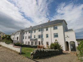 A building with multiple windows and a garden area at Cwtch y Môr in Trearddur Bay