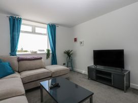A living room with a sofa and television at Cwtch y Môr in Trearddur Bay
