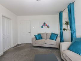 A living room with a sofa and artwork at Cwtch y Môr in Trearddur Bay