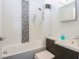 A bathroom with a bathtub, shower, sink and mirror at Cwtch y Môr in Trearddur Bay
