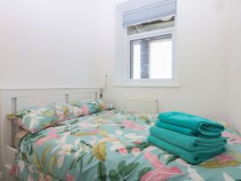 A bedroom with a bed, pillows, towels, and a window at Cwtch y Môr Trearddur Bay