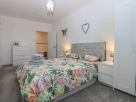 A bedroom with a bed, nightstand, dresser and decor at Cwtch y Môr in Trearddur Bay