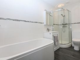 A bathroom with a bathtub, shower, toilet, and sink at Cwtch y Môr in Trearddur Bay