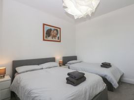 A bedroom with two beds and a picture on the wall at Cwtch y Môr in Trearddur Bay