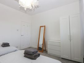 A bedroom with two beds and a wardrobe at Cwtch y Môr in Trearddur Bay