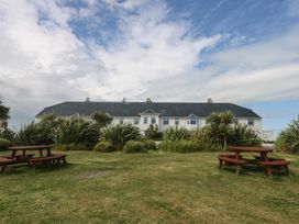 A building with picnic tables and grass at Cwtch y Môr in Trearddur Bay