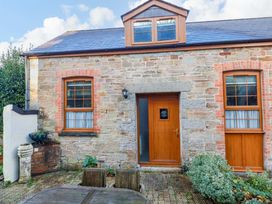 An exterior view of a stone building with wooden door and windows at The Stables in Falmouth
