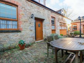 An outdoor area with a stone wall and wooden furniture at The Stables in Falmouth