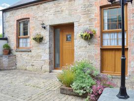 An outdoor entrance with a wooden door and flower pots at The Stables Budock Water near Falmouth