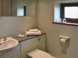 A bathroom with a sink, toilet, and towels at The Stables Budock Water near Falmouth