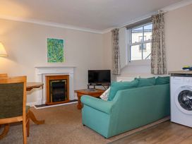 A living room with a sofa, television and fireplace at Horseshoe Cottage in Falmouth
