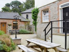 An outdoor area with a wooden table and chairs at Horseshoe Cottage Budock Water near Falmouth