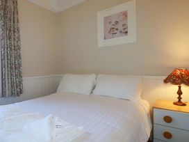 A bedroom with a bed and nightstand at The Hayloft in Falmouth