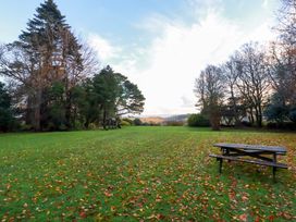 A garden with trees and a table at The Hayloft in Falmouth