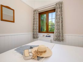A bedroom with a window, mirror, and bed at The Hayloft in Budock Water near Falmouth