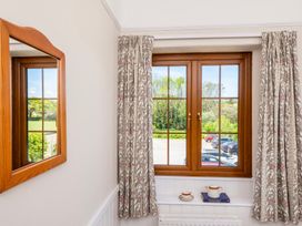 A room with a window and mirror at The Hayloft Budock Water near Falmouth